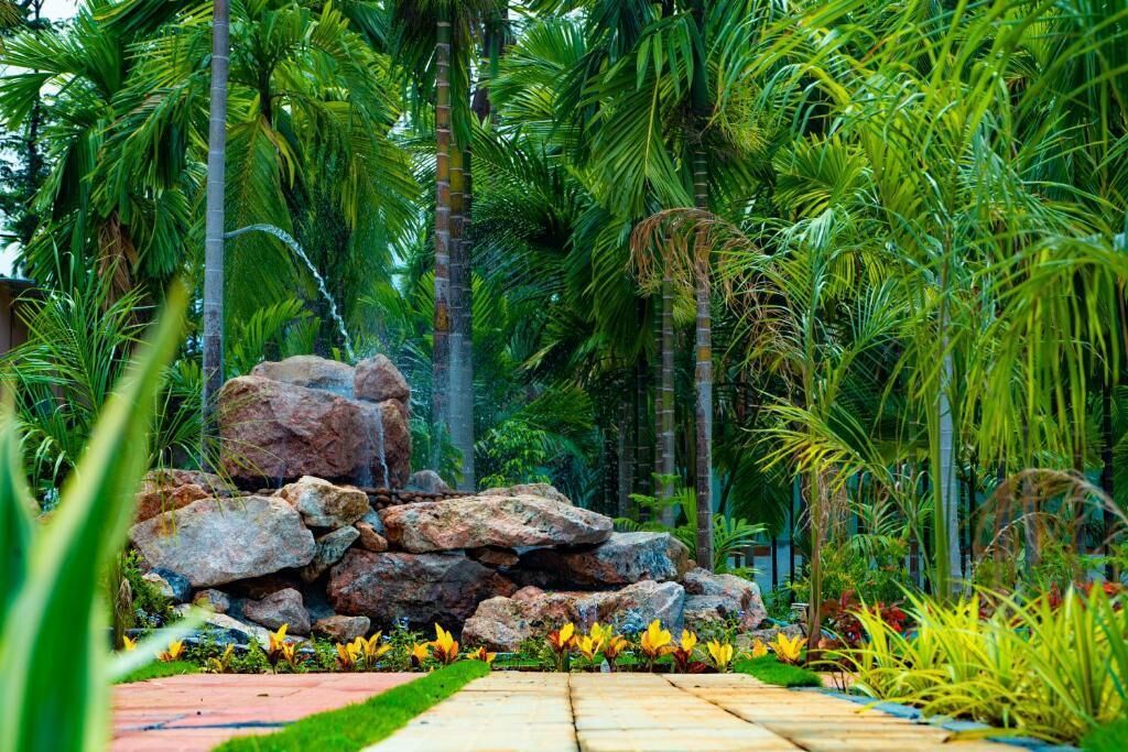 A garden with a stone pathway, tropical plants, and a rock formation.