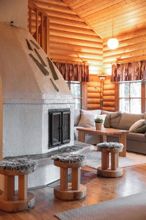 Interior acogedor de una cabaña de troncos, con chimenea, muebles de madera y un rincón de estar confortable.