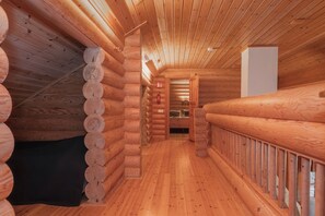 A log cabin interior with a central hallway, wooden walls, and a wooden floor.