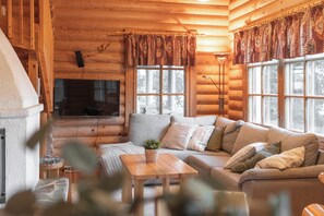 Interior acogedor de una cabaña de troncos con sofá, mesa y chimenea.