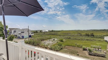Ein Balkon mit Blick auf ein grasbewachsenes Feld, einen weißen Zaun und ein Gebäude mit grauem Dach.