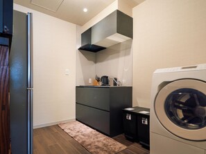Une petite buanderie comprenant un lave-linge, un sèche-linge et un petit plan de travail sur lequel est posée une machine à café.
