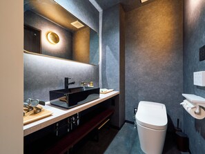 Ein modernes Badezimmer mit einem schwarzen Waschbecken, einem Spiegel und einer Toilette.