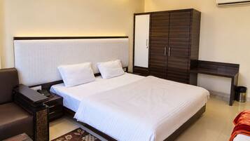 A hotel room with a large bed, a bedside table, a wardrobe, and a desk.