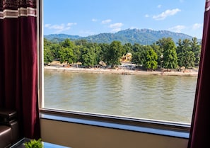A river view with a mountain in the background, a bridge, and a building with a dome. - Anand Niketan (Haridwar)