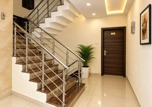 Un interior moderno con una escalera, una planta en maceta, una puerta y un cuadro en la pared.