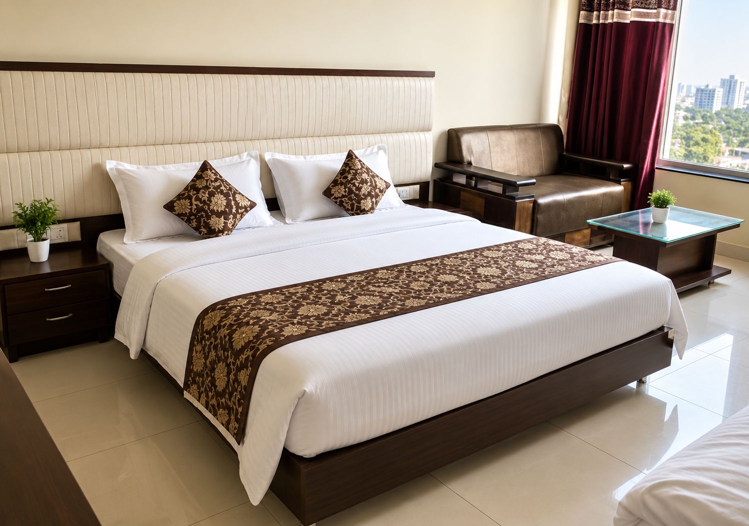Habitación de hotel con una cama grande, una mesita de noche, una silla, una pequeña mesa y un ventanal con cortinas.