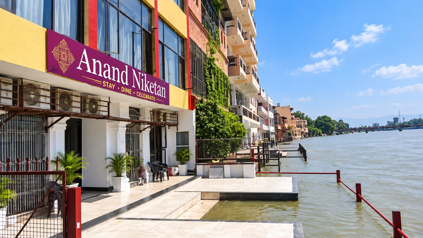 A waterfront hotel with a prominent sign reading 'Anand Niketan.'