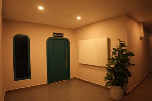 Un pasillo con dos puertas que indican 'BEER & WINE', una planta en maceta y un aplique de pared.