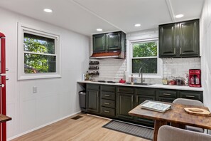 A compact kitchen with dark cabinets, a white countertop, and a window providing natural light.