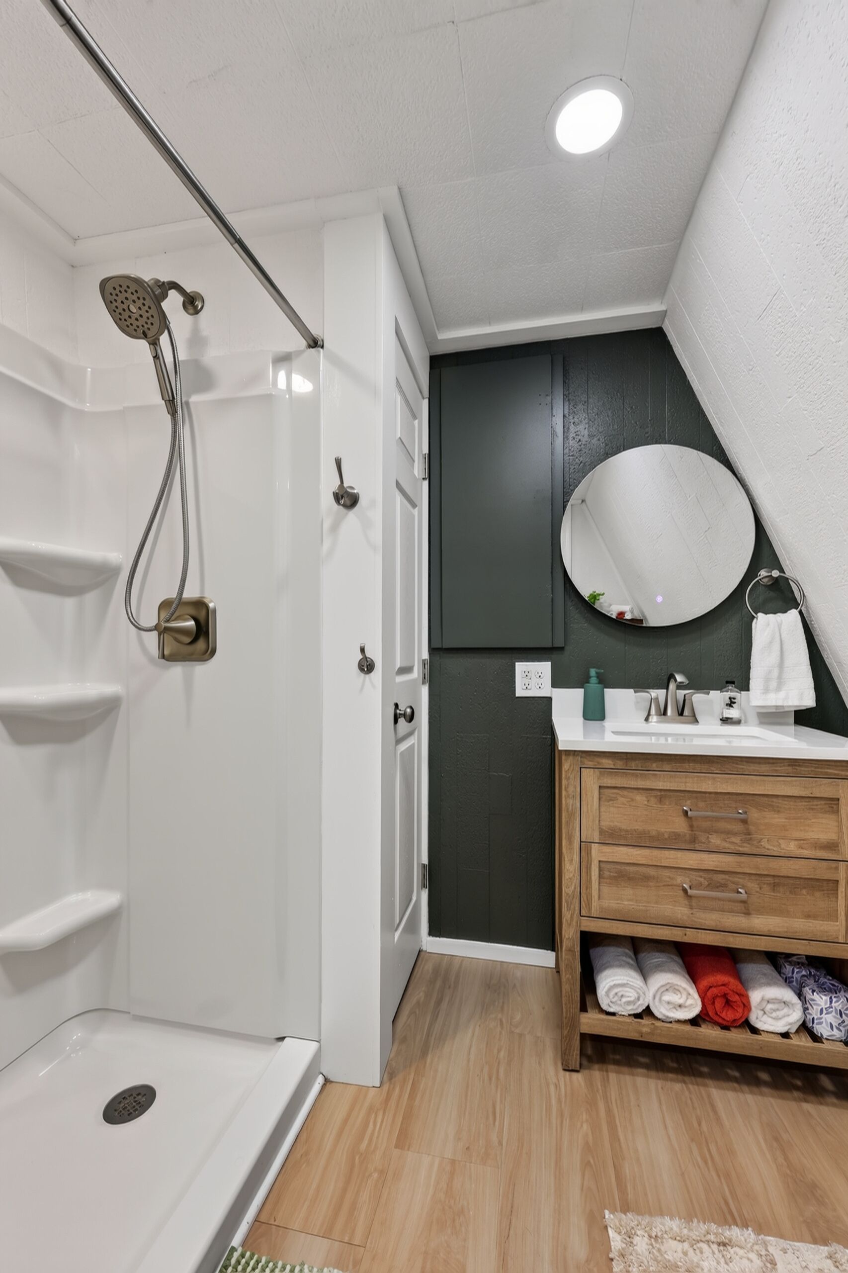 A modern bathroom with a shower, a vanity with a mirror, and a towel rack.