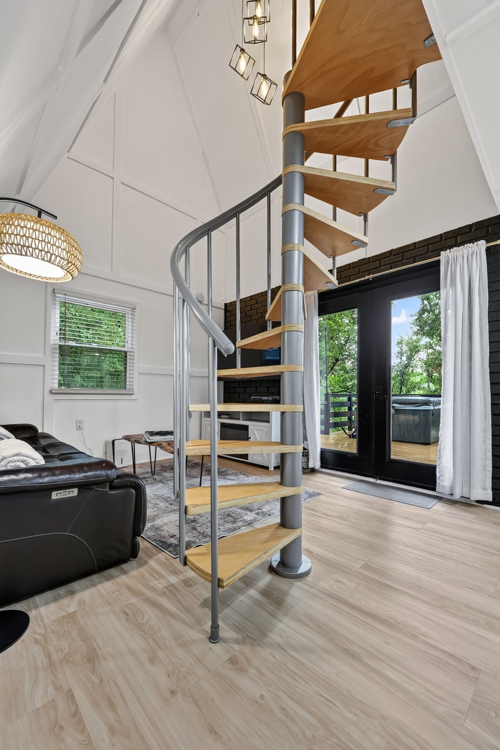 A modern interior with a spiral staircase, a leather sofa, and a view through a glass door.