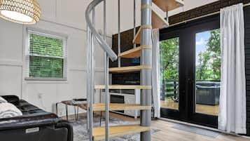 A modern interior with a spiral staircase, a leather sofa, and a view through a glass door.
