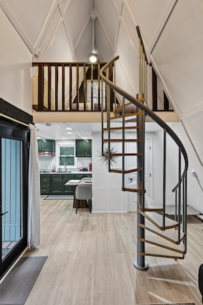 A spacious loft with a spiral staircase connecting two levels, a kitchen with modern appliances, and a dining area.
