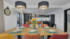 A dining area with a wooden table, green placemats, and chairs with orange and red cushions. - Villa Baculla by Villas Guide (Makarska)