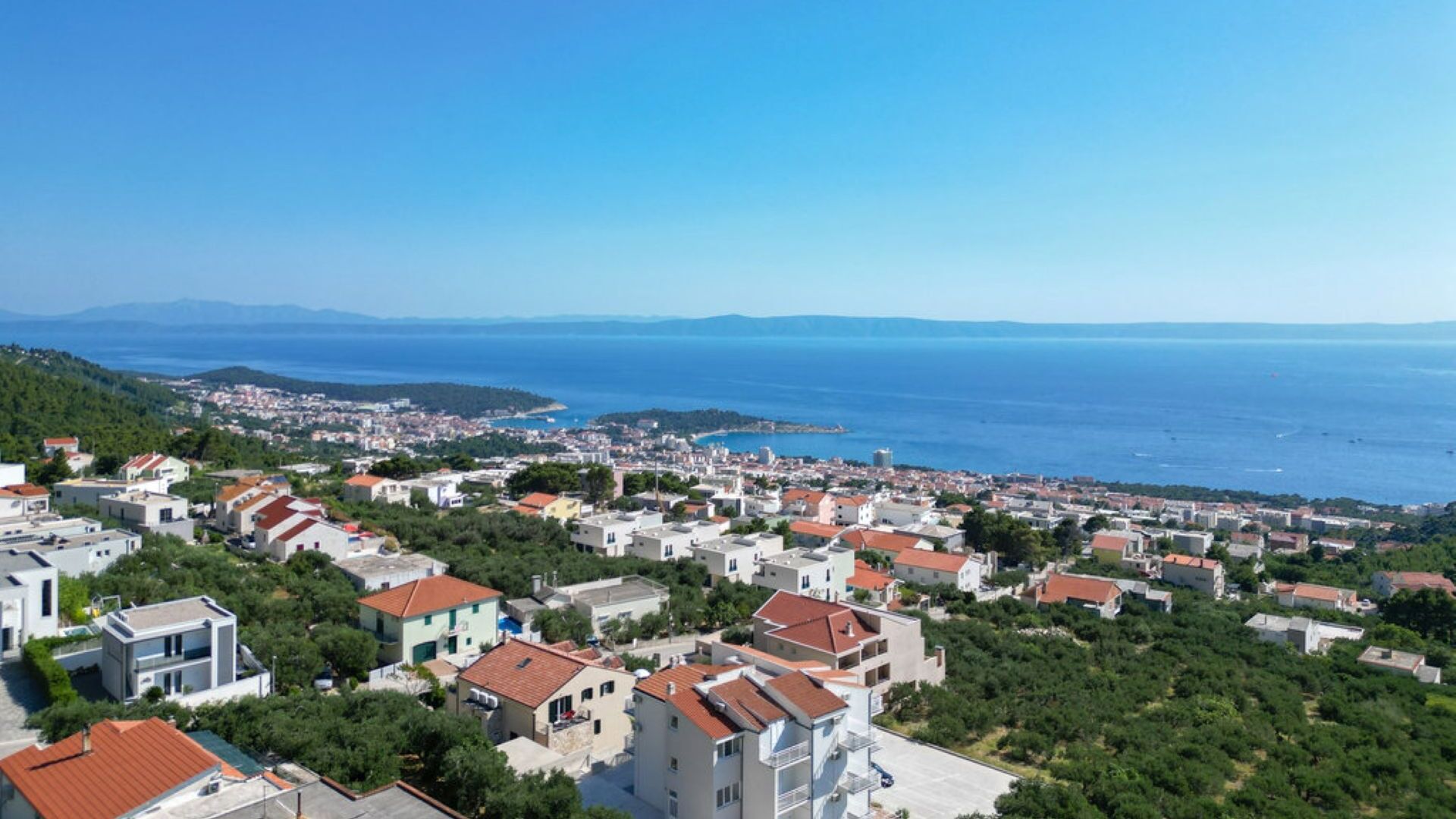Eine Küstenstadt mit Gebäuden, Grünflächen und Blick auf das Meer.