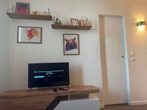 Ein Wohnzimmer mit Fernseher, der eine Fehlermeldung anzeigt, Holzregalen mit Dekoration und einer Tür mit Wandleuchte.
