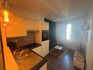 Eine kleine Küche mit Spüle, Backofen und einem Essplatz.