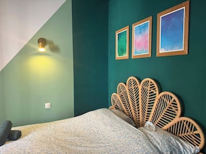 A room with a bed, a wall-mounted light, and three framed pictures. - Charming 2-Bedroom Apartment in Paris's Vibrant 19th Arrondissement (Paris)