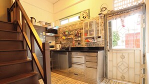 Eine Küche mit einer Holztreppe, Edelstahlgeräten und einer gefliesten Spritzschutzwand.