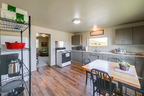 Una cocina moderna con zona de comedor, piso de madera y vistas por la ventana.