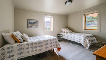 A bedroom with two beds, a window, and a ceiling light.