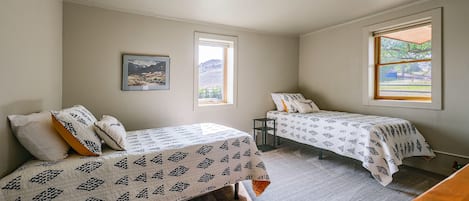 A bedroom with two beds, a window, and a ceiling light.