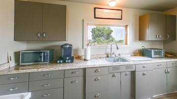 A kitchen with a window, a sink, a microwave, a toaster, and cabinets.