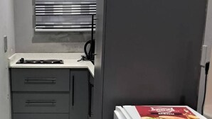 A compact kitchen with a built-in stove, a microwave, and a refrigerator.