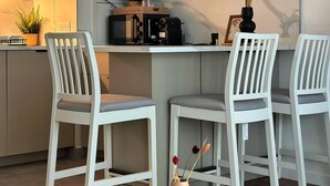 Eine moderne Küche mit weißen Schränken, einer Kaffeemaschine und zwei weißen Stühlen.