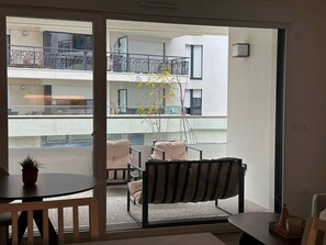 A balcony with a sofa, chairs, a small table, and a potted plant. - Charming Colombes Apartment  Comfort, Convenience, and Style (Colombes)