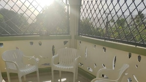 A covered outdoor seating area with plastic chairs and a tiled floor.