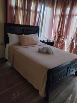 A bed with a headboard, pillows, and a neatly folded towel on the bed.