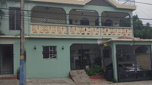 A two-story building with a balcony, a covered entrance, and a gated driveway.