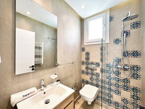 Un bagno con lavandino, specchio, porta asciugamani, doccia e WC.