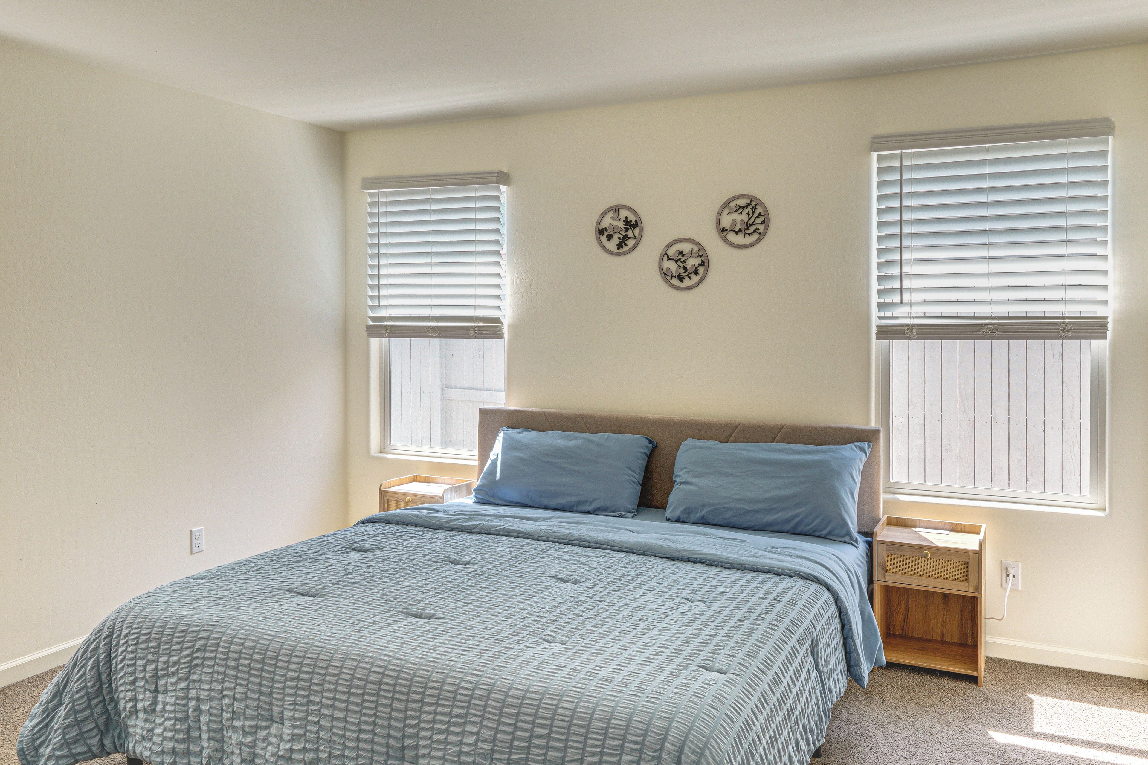 Ein Schlafzimmer mit einem Bett, zwei Nachttischen, einem Fenster mit Rollläden und Wanddekoration.