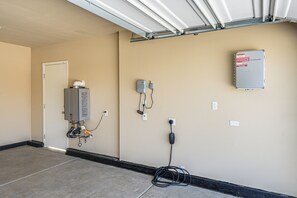 Une pièce utilitaire équipée d’un chauffe-eau, de prises électriques et d’un panneau de commande mural.