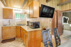 A compact kitchen with wooden cabinets, a microwave, and a flat-screen TV mounted on the wall. - Catskills Group Retreat: 2 Cabins w/ Pool Access! (Mongaup Valley)
