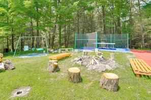 Ein bewaldetes Gebiet mit Schaukel, Bank, Tisch und Feuerstelle.