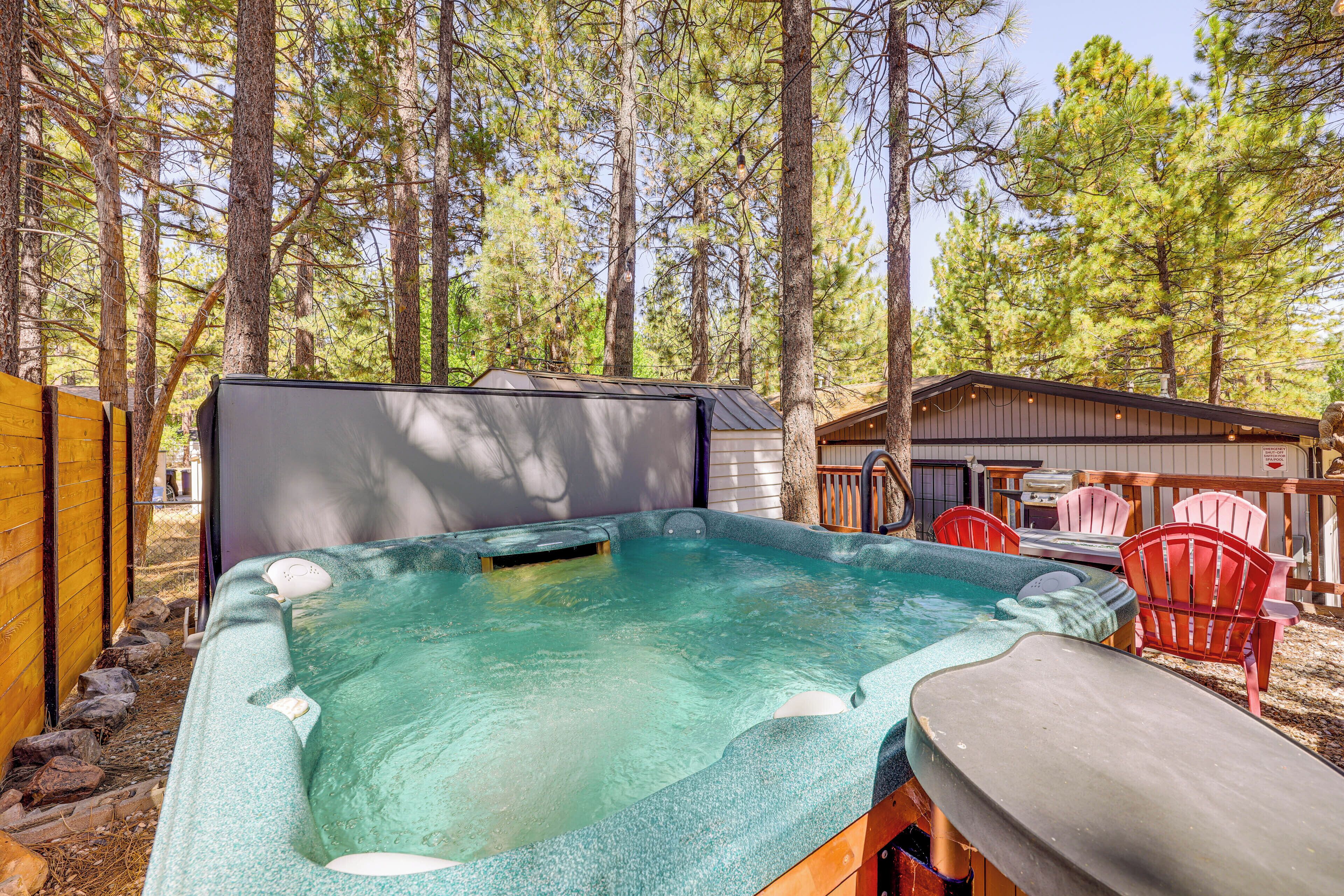 A hot tub surrounded by a wooden deck, with a shed and outdoor seating area in the background.