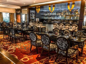 A bar area with a long counter, multiple chairs, and a patterned carpet.