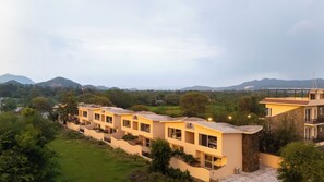Un hotel moderno con varios pisos, amplias ventanas y vistas a zonas verdes y colinas.