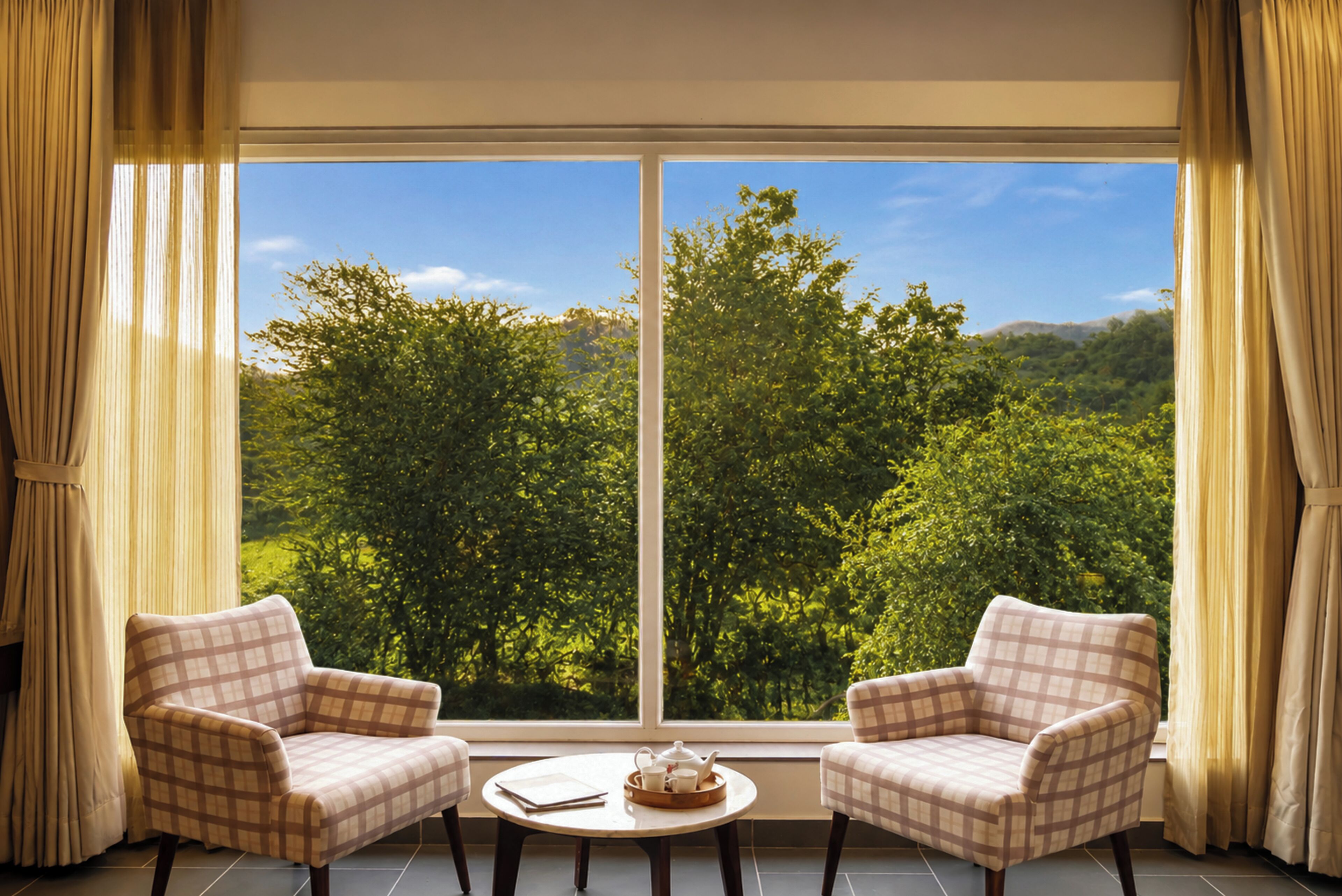 Una habitación con dos sillones orientados hacia una ventana grande que da a un paisaje boscoso.