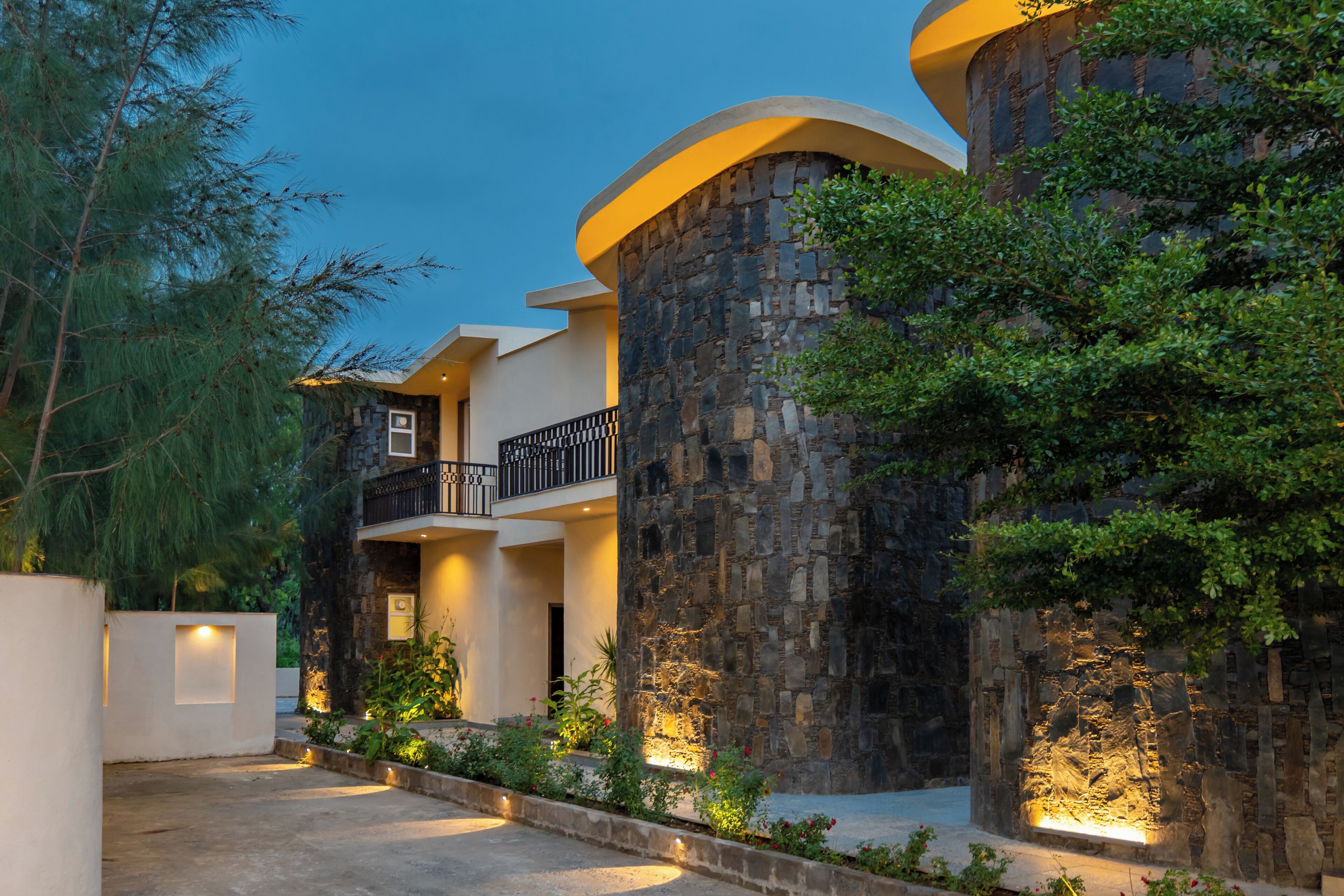 A multi-story building with a stone facade, a balcony, and a well-lit entrance.