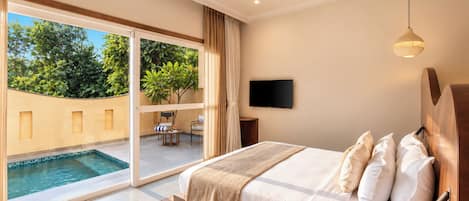 A bedroom with a large bed, a TV mounted on the wall, and a view of a swimming pool through a sliding glass door.