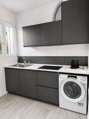 A modern kitchen with a built-in washing machine, a sink, and a coffee maker.