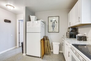 A compact kitchen with white cabinets, a refrigerator, a toaster, and a trash bin. - Bear Lake Cabin w/ Spacious Yard + Patio! (Saint Charles)