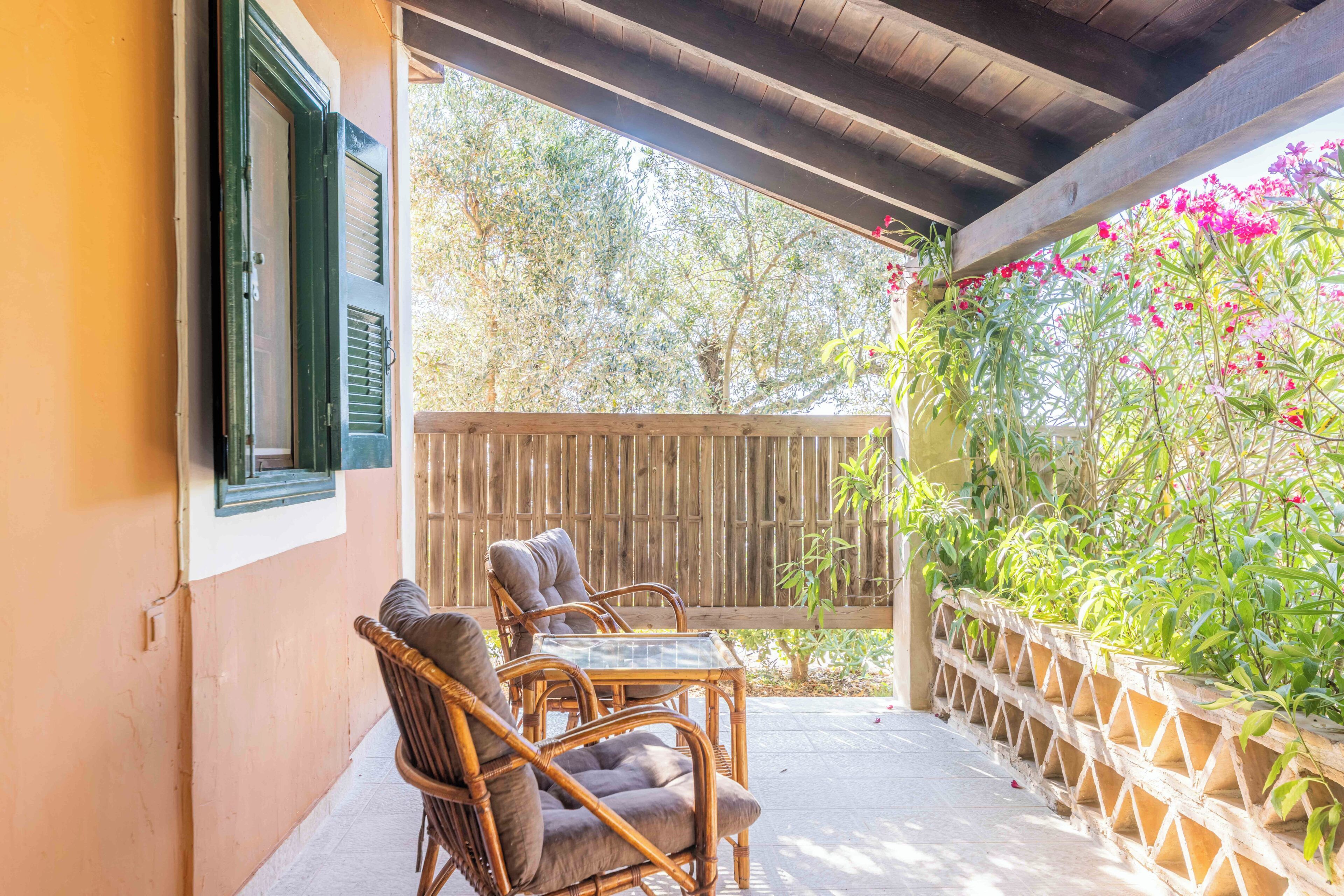 A covered patio with wicker furniture and a wooden fence.