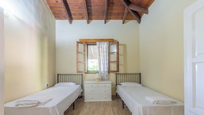 A room with two single beds, a small white dresser, a window with a wooden frame, and a wooden ceiling. - Zanteva-Psophis cottage (Zakynthos)