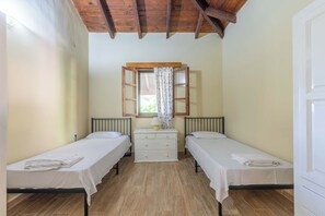 A room with two single beds, a small white dresser, a window with a wooden frame, and a wooden ceiling. - Zanteva-Psophis cottage (Zakynthos)